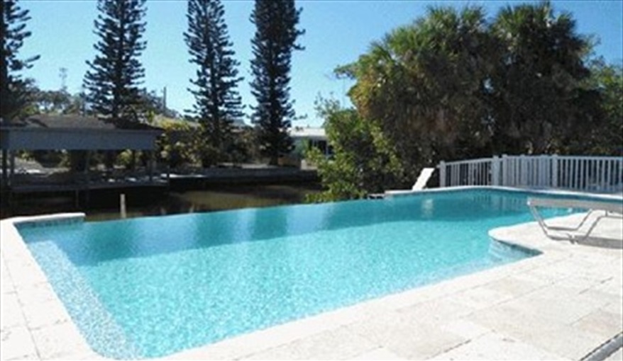 Full bench seat across the shallow end for sipping that cool drink while the jets massage your back.. Island Villa with 33 Foot Infinity Pool, Dock, Dolphin Visits in Fort Myers Beach, Fort Myers, Gulf Coast